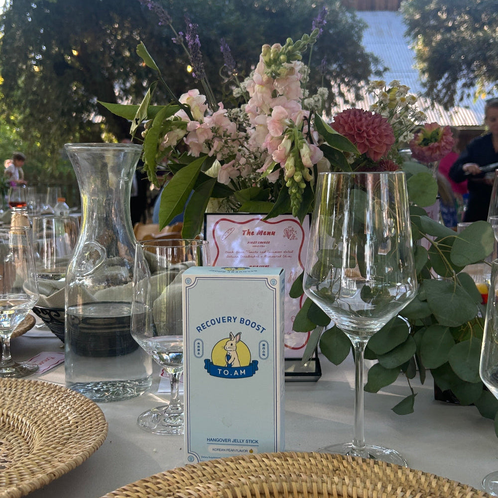 Set table with wine glasses, flowers, and TO. AM box outdoors.
